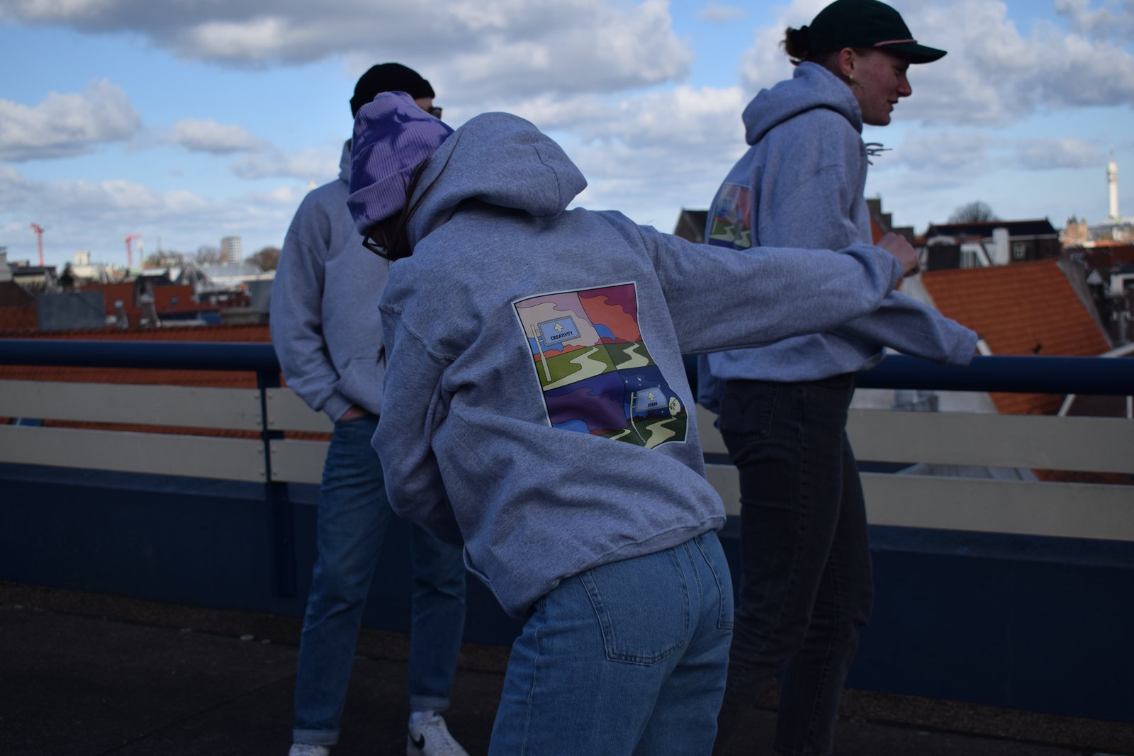 Model leaning forward to show the illustrated back print of a SFERE hoodie
