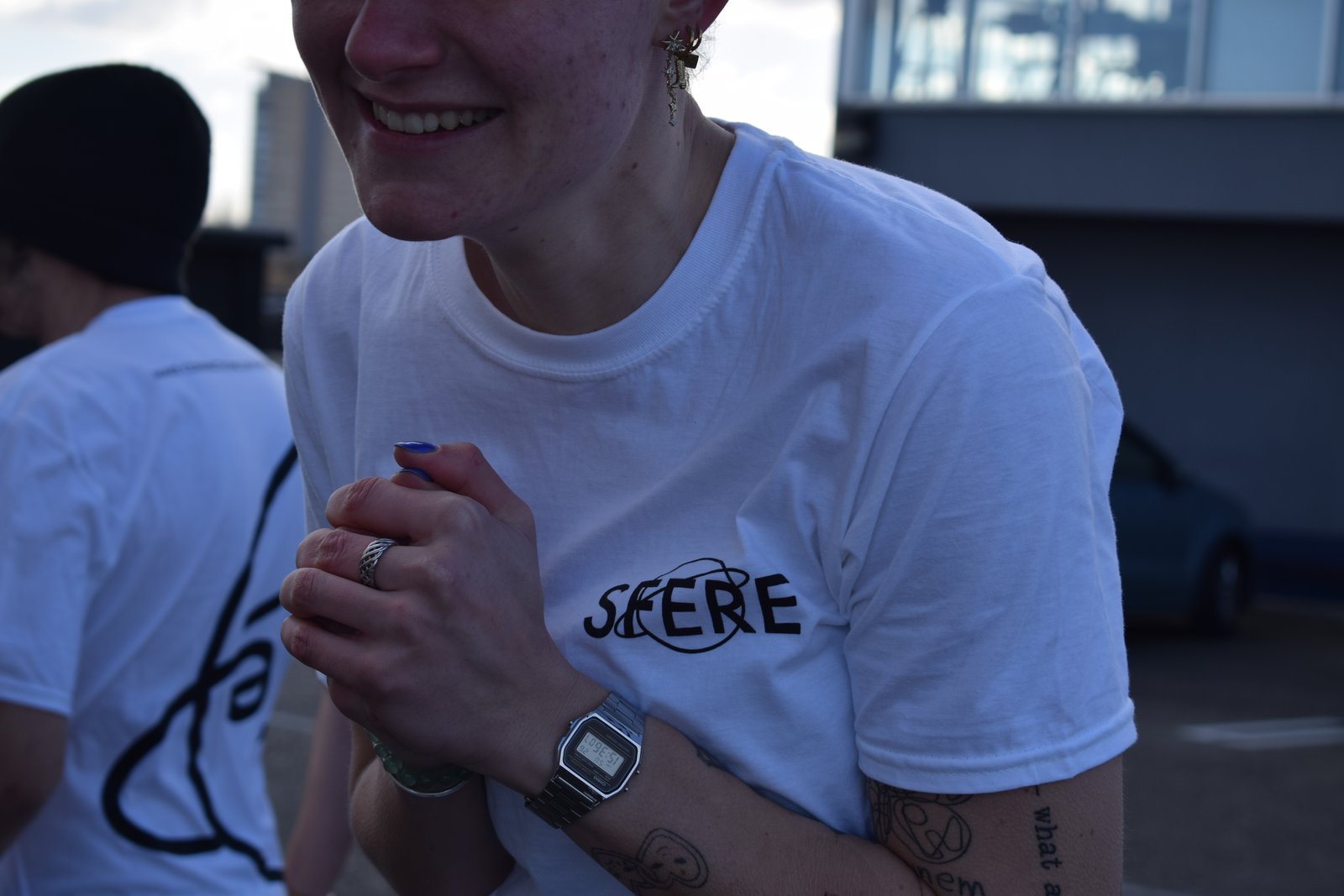 Close-up of a smiling model in a white SFERE logo t-shirt