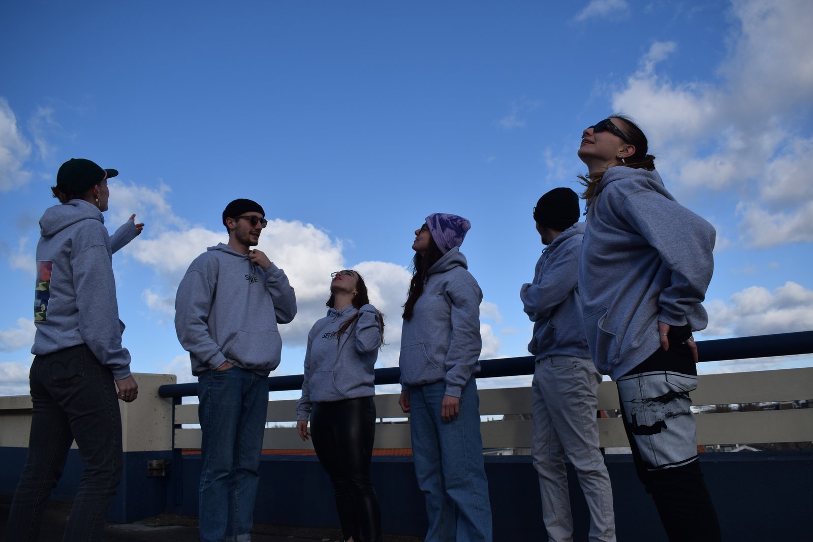 Group in SFERE hoodies on a rooftop, gazing up at a blue sky