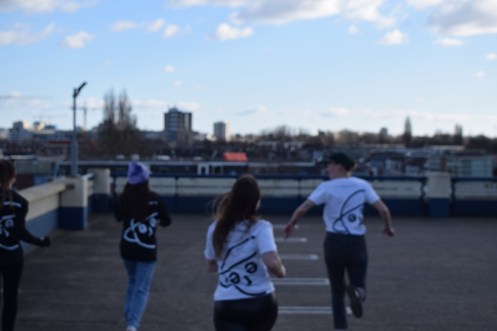 Models in SFERE t-shirts running across a rooftop, softly out of focus