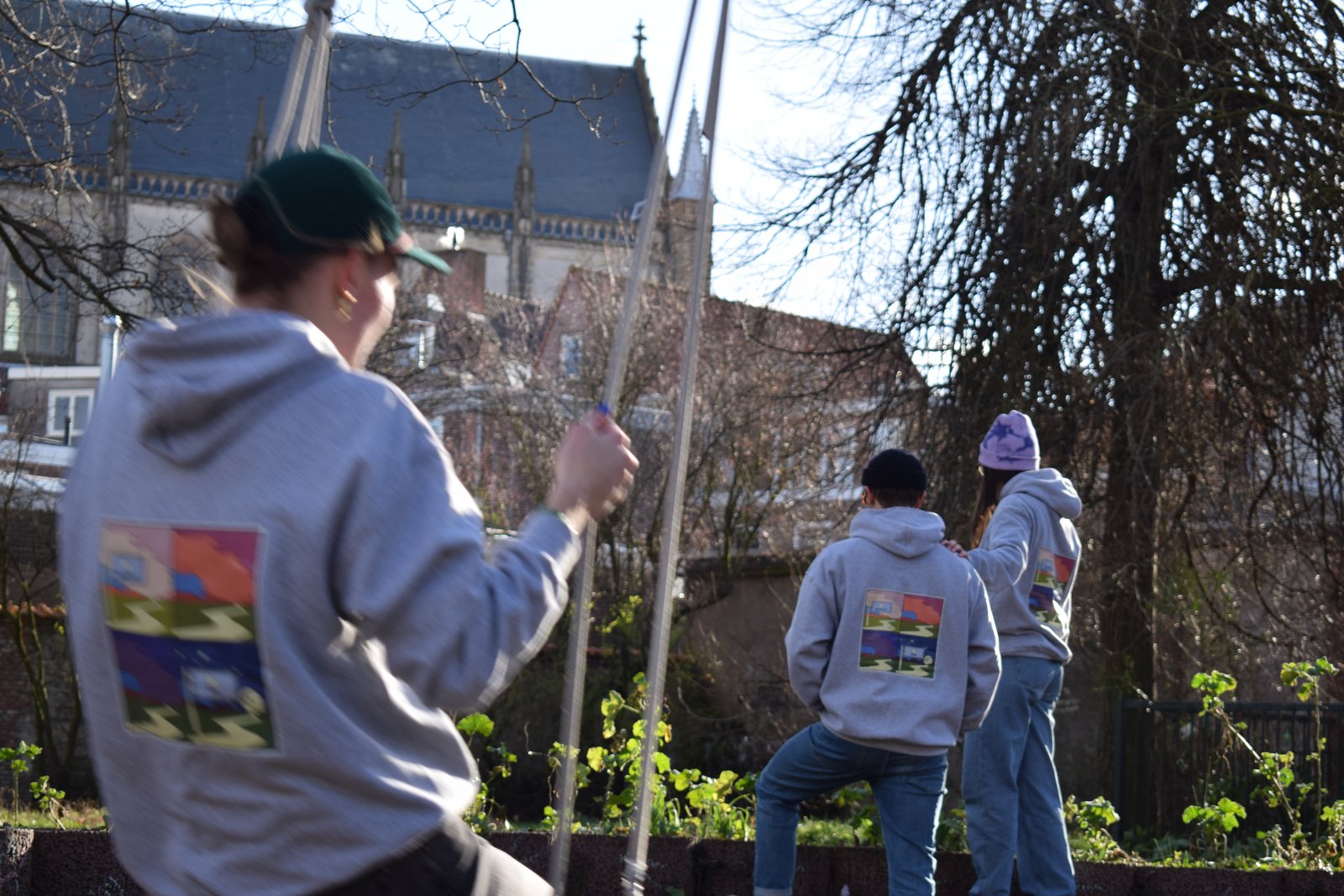 Models in SFERE hoodies in a garden beside a church